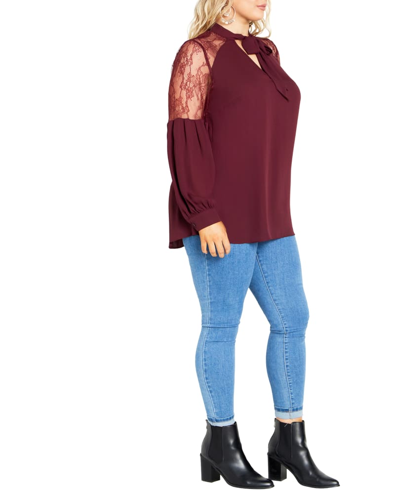 Side of a model wearing a size S Lacey Hi Lo Top in Oxblood by City Chic. | dia_product_style_image_id:318091